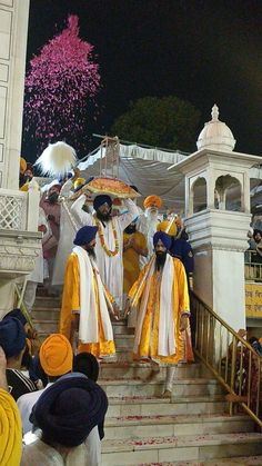 men dressed in yellow and white are walking down the stairs