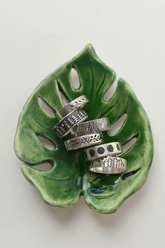 four different rings sitting on top of a green leaf shaped object with holes in the middle