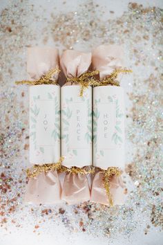 three wrapped gift boxes sitting on top of each other with gold ribbon and bows around them