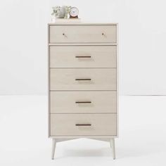 a white dresser with five drawers and two clocks on it's top, against a white background