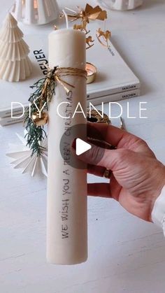 a person is holding a white candle in front of some christmas decorations on a table