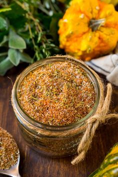 a glass jar filled with seasoning next to other spices and herbs on a wooden table