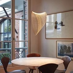 a dining room table with four chairs and a light fixture hanging from it's ceiling