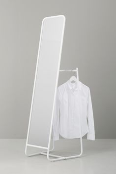 a white clothes rack with a shirt on it and a mirror in front of it