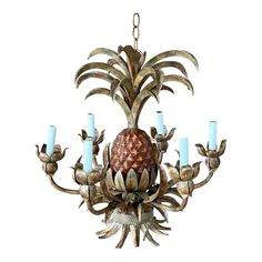 a chandelier with five lit candles hanging from it's center and an ornate pineapple design