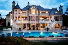 a large mansion with a swimming pool in the front yard and stairs leading up to it