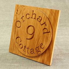 a wooden plaque with the words orchard cottage engraved on it's side, in front of a plain background