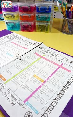 a binder sitting on top of a table filled with lots of colorful boxes and pencils