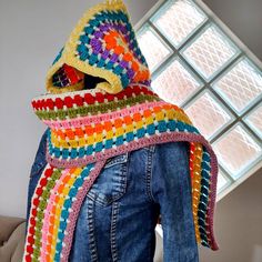 a colorful crocheted scarf hanging from the back of a woman's jacket