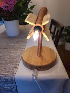 a wooden table with a light on top of it and flowers in the back ground