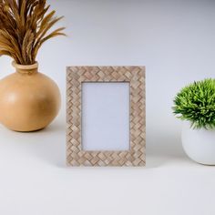 an empty photo frame sitting next to a potted plant