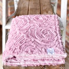 a pink blanket sitting on top of a wooden bench