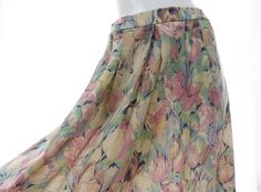 Vintage Liberty of London fabric skirt with a floral print in shades of pink, blue, green, peachy-beige, ivory, and mauve. Material is a lightweight wool without stretch. It is hand washable or dry cleanable. Estimated era: 1980s.  This unlined pleated skirt is partially elasticized along the sides of the waist. It has a back zip with clasp closure, and two hand pockets. It may have been hemmed up slightly -- will hit below the knee to mid calf on most.  Good vintage condition overall, however the elastic at the sides of the waist has slackened (not completely), and there are a couple of small pulls and faint stains as shown. As-is.  Size on tag: large, however please go by the following approximate measurements, taken flat: Waist, across the front and doubled: 31" unstretched to 35" fully Spring Beige Silk Skirt, Fabric Skirt, Liberty Of London Fabric, Skirt Pleated, Floral Print Skirt, Liberty Of London, Print Skirt, Printed Skirts, Mid Calf