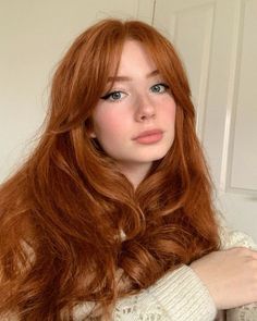 a young woman with long red hair is posing for the camera while wearing a sweater