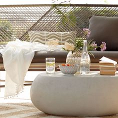 a coffee table with books and vases on it in front of a brown couch