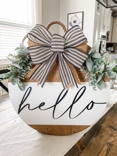 a wooden sign with a bow on it that says hello