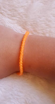 A bright orange beaded bracelet. With round beads and white string. Aesthetic orange. Trendy Orange Friendship Bracelets As Gift, Trendy Orange Friendship Bracelets Gift, Trendy Orange Friendship Bracelet Gift, Trendy Orange Beaded Friendship Bracelets, Trendy Orange Beaded Bracelets For Friendship, Trendy Orange Jewelry With Tiny Beads, Casual Orange Beaded Bracelets, Casual Orange Beaded Bracelet, Orange Round Beads Friendship Bracelets As Gift