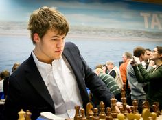 a young man playing chess in front of a large group of people