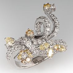 This lovely ring features a floral and ribbon design and is prong set with a total of fifty-one (51) round brilliant cut diamonds and four (4) marquise brilliant cut diamonds. The ring measures 21.1mm at the top, rises 6.4mm above the finger, tapering to 2.9mm wide and 1.2mm thick at the base of the shank. This ring is currently a size 6.5. Luxury Marquise Multi-stone Diamond Ring, White Gold Marquise Multi-stone Diamond Ring, Luxury Marquise Cut Multi-stone Diamond Ring, Luxury Multi-stone Marquise Cut Diamond Ring, Marquise Multi-stone Diamond Ring, Platinum Multi-stone Diamond Wedding Ring, Elegant Multi-stone Pear-shaped Diamond Ring, Marquise Multi-stone Diamond Wedding Ring, Cubic Zirconia Marquise-cut Multi-stone Diamond Ring