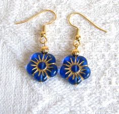 Pretty blue Czech glass flower beads with gold accents and a gold bead on top makes for a simple yet elegant earring. The small flower is 5/8" wide, with a total earring length of 1 1/2" / 38mm. The ear wires are gold plated stainless steel. These are quality ear wires with no nickel or lead for a no-allergy finish. I will change your earwires to gold plated clip-ons if chosen at checkout. Shipping is charged for the first pair of earrings only. Please look around my shop and find more earrings Handmade Gold Flower Earrings With Czech Glass, Gold Beaded Flower Earrings, Gold Nickel-free Czech Glass Flower Earrings, Nickel-free Gold Czech Glass Flower Earrings, Nickel-free Gold Flower Earrings With Czech Glass, Gold Beaded Flower-shaped Earrings, Gold Czech Glass Flower Earrings For Gift, Adjustable Gold Beaded Flower Earrings, Gold Flower-shaped Czech Glass Earrings