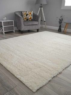 a white rug in a living room with a gray chair and grey carpet on the floor