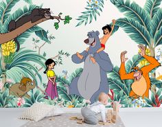 a baby playing with toys in front of a jungle scene wallpapered with cartoon characters