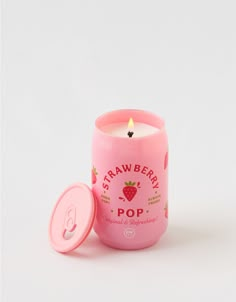 a pink cup with a candle in it sitting next to a white container that says strawberry pop