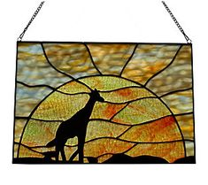 a stained glass window with a giraffe standing in front of the sun at sunset