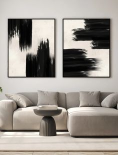 two black and white paintings hanging on the wall above a couch in a living room