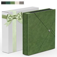 an open green book with a bow on the front and side, sitting next to a white box