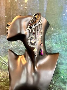 a mannequin head with earrings on it in front of a forest background and stars