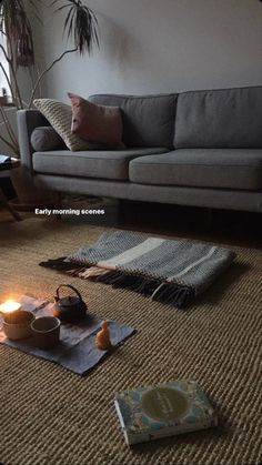 a living room with a couch, rugs and candles on the floor in front of it