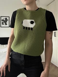 a woman wearing a green knitted sweater with black sheep on the front and white sheep on the back