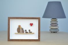 a wooden frame with some rocks in it and a lamp on the table next to it