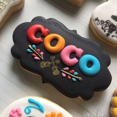 decorated cookies with the word coco on them are displayed in front of other decorated cookies