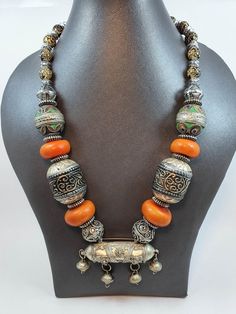 Feel the beauty of Moroccan heritage with this exquisite Berber necklace. Handcrafted by artisans, this stunning piece of jewelry tells stories of the ancient Amazigh culture and its predecessors, captivating you with its beautiful orange enamel and sculpted metal components. Every time you wear it, you will feel a unique connection to the tribal ancestors. Add a touch of elegance to your look with this timeless piece of jewelry! Length:40 cm End to end Length: 74 cm Please be aware that due to Bohemian Bronze Pendant Jewelry, Bronze Bohemian Pendant Jewelry, Traditional Handmade Necklaces For Festival, Handmade Traditional Necklace For Festivals, Bohemian Bronze Beaded Jewelry, Long Necklaces For Rituals And Festivals, Vintage Large Pendant Jewelry For Rituals, Vintage Jewelry With Large Pendant For Rituals, Vintage Amber Jewelry With Large Beads