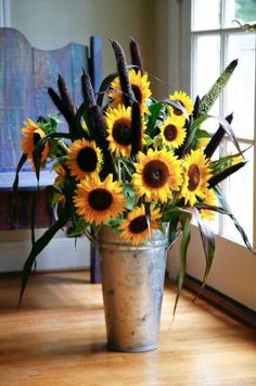 a vase filled with lots of sunflowers sitting on top of a wooden floor