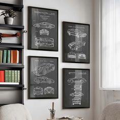 three framed cars are hanging on the wall next to a chair and bookshelf