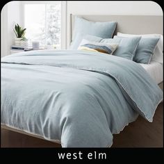 the bed is made with blue linens and pillows