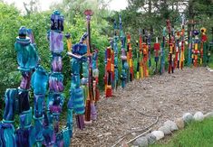 many different colored vases are lined up on the ground in front of some trees