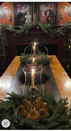 a candle is lit on top of a table with pine cones and greenery around it