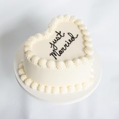 a white heart shaped cake with writing on it