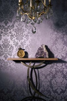 a table topped with a crystal ball next to a purple wallpaper covered in damask