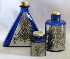 three blue and silver vases sitting next to each other