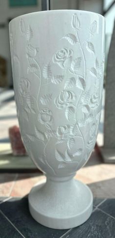 a white vase sitting on top of a tiled floor