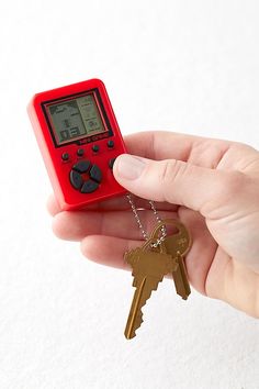 a hand holding a keychain with a digital clock on it and two keys attached to it