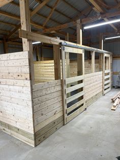 the inside of a horse barn with wooden stalls