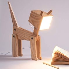 a wooden dog lamp sitting on top of a table next to an open book with a light coming from it