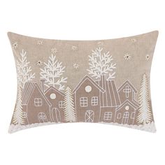 a decorative pillow with houses and trees on the front, in beige linen fabric that has white snowflakes all over it