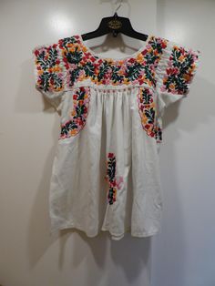 Vintage San Antonio Embroidered Mexican Wedding Blouse with Little People Pink Floral. Oaxacan Embroidered shirt done on a white cotton blend. This shirt is in very good condition but has minor pilling on the fabric and a few areas. Medium heavy embroidery and crocheted trim. Embroidery is hand done not machine. The yoke is the key to the sizing on these shirt. I am calling this one a Medium.  yoke  14" X 12" pit to pit measured in the middle of the gusset under the armpit 17" so 34" bust  shoulder to hem 27" from a no smoke home Shipping included in price Folk Style Fitted White Embroidered Top, Fitted Folk White Top, Fitted White Folk Top, White Fitted Folk Top, Fitted White Folk Style Top, White Fitted Folk Style Top, White Folk Embroidered Top For Festival, White Cotton Folk Embroidered Top, White Folk Style Embroidered Cotton Top